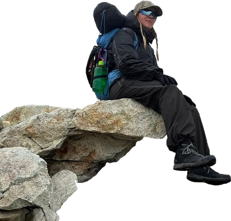 Kash sitting on a rock with a backpack full of gear on